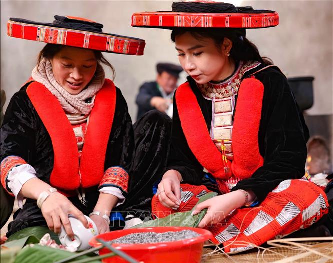 Nữ du khách tới từ Hà Nội trong trang phục truyền thống của người Dao đỏ huyện Nguyên Bình háo hức cùng gói bánh chưng gù ngày Tết. Ảnh: Thanh Tùng - TTXVN